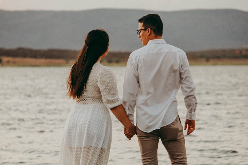 Couple holding hands looking out over a lake together